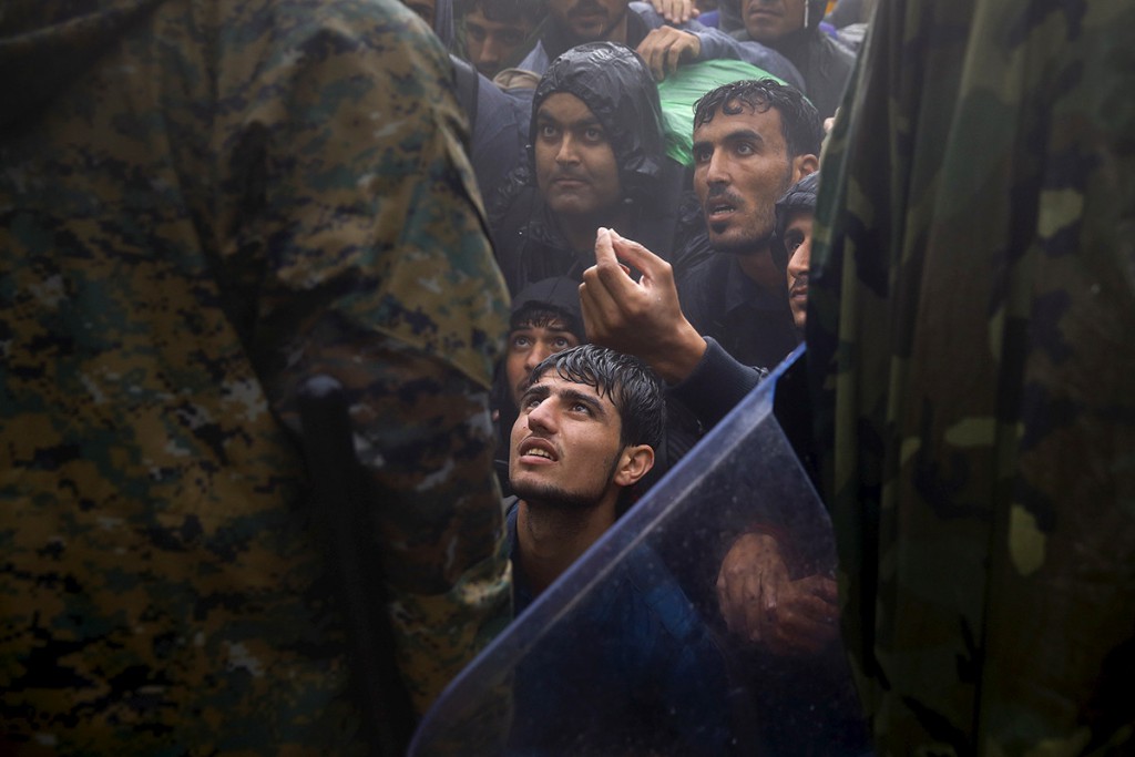 Migrantes y refugiados piden a policias macedonios que les den paso para cruzar la frontera de Grecia hacia Macedonia durante una tormenta, cerca de Idomeni. 10/09/2015